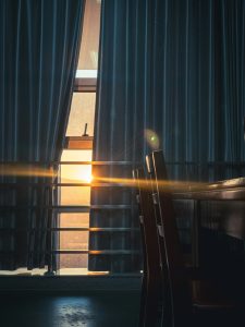 Sonnenlicht fällt durch dunkle Vorhänge in einen Raum