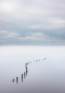 Ruhige Wasserlandschaft mit Pfählen im stillen Wasser